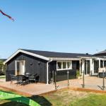 Ein schwarzes Haus mit Terrasse und dänischer Flagge. Gartenmöbel und Sonnenschirm.