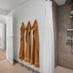 Dusche mit Duschbrause und drei gelbe Handtücher an der Wand.