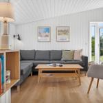 Wohnzimmer mit grauem Sofa, Holztisch und Bücherregal. Durchgang zur Terrasse.