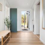 Hausflur mit Holzboden, Wandbildern, Pflanze und Spiegel