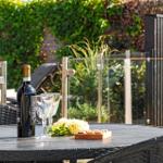 Runder Tisch mit Weinflasche, Gläsern und Blumen im Garten