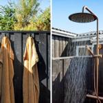 Zwei goldene Handtücher hängen an einem schwarzen Zaun. Eine Dusche mit goldener Armatur und Wasserstrahl.