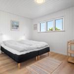 Schlafzimmer mit Doppelbett, Fenster und Holzboden.