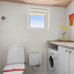 Toilette, Waschmaschine und Waschbecken mit Fenster und Bild.