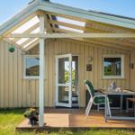 Haus mit Terrasse, Tisch, Stühlen und grünem Hängemobil.