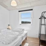 Room with double bed, window, and coat rack
