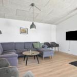 Living room with sofa, armchairs, coffee table, and wood-burning stove. Concrete ceiling panels.