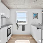 Modern kitchen with white cabinets, countertop, and window view.