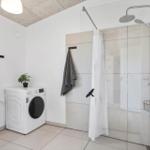 Bathroom with shower, washing machine, and mirror