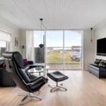 Living room with black leather furniture, wooden floor, and large window to terrace.