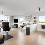 Living room with wooden floor, black chairs, TV, and windows with views outside.