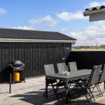 Terrace with table, chairs, and grill. Background: black-clad wall and grassland.