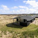 Modern holiday home with terrace in dune landscape, view of beach and sea.
