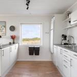 Kitchen with white built-in cabinetry, dark worktop, and window view of grassland.