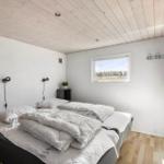 Bedroom with double bed, wooden floor, and window. Ceiling made of wood, wall shelves, and nightstands.