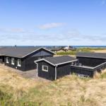Black wooden houses on dunes with sea view and wooden terrace.