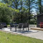 Terrasse mit Sitzgruppe, Tisch und Stühlen. Roter Bank neben Holzhaus. Grün hinter dem Haus.