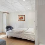 Schlafzimmer mit Bett, Stuhl und Fenster. Wandbild und Kleiderschrank sichtbar.