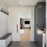 Eingangsbereich mit Garderobe, Sitzbank und Blick in Wohnzimmer mit Kamin und Fernseher.