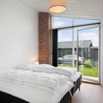 Schlafzimmer mit Doppelbett, großem Fenster und Blick auf Garten.