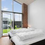 Schlafzimmer mit weißem Bett und großem Fenster zur Außenterrasse.
