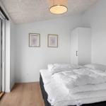 Schlafzimmer mit Bett, Schrank und Fenster zur Terrasse.