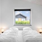 Zwei Betten mit weißen Bettwäschen unter einem Fenster mit Blick auf ein Haus.