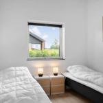 Zwei Betten mit weißen Bettwäschen, Nachttische mit Lampen und ein Fenster mit Blick auf Grün.