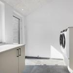 Wohnung mit Waschmaschine und Fenster. Fliesenboden und weiße Wände.