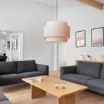Wohnzimmer mit zwei grauen Sofas, Holztisch und Deckenleuchte.