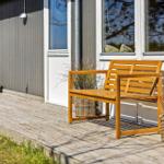 Wooden bench on terrace in front of house with windows and plants in baskets.