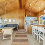 Living and dining area with wooden walls, kitchen island, and windows.