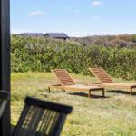 Two wooden lounge chairs on a lawn with view of shrubs and houses.