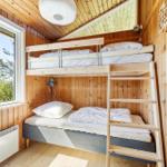 Bedroom with bunk bed, wooden walls, and window with view of trees.