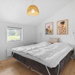 Schlafzimmer mit Bett, Fenster und Wandbildern.