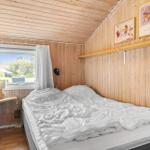 Schlafzimmer mit Holzwand, Bett und Fenster mit Blick nach draußen.