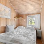 Schlafzimmer mit Holzwand, Bett und Fenster mit weißen Vorhängen.