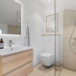 Badezimmer mit Dusche, Waschbecken und Toilette. Holzunterschrank und Spiegel mit Beleuchtung.