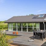 Moderne Villa mit großem Holzterrasse, Gartenmöbel und großflächigen Fenstern.