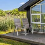 Terrasse mit zwei Liegestühlen vor einem Haus mit großem Fenster.
