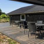 Terrasse mit Tisch und Stühlen vor einem Holzhaus mit schwarzem Dach.