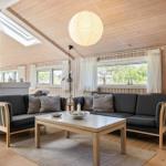 Wohnzimmer mit Holzwand, Sofa, Tisch und Lampe. Fenster und Dachfenster.