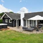 Modern holiday home with outdoor terrace, sun umbrella, seating, and hot tub in garden.
