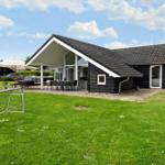 Black wooden house with terrace and garden. Outdoor table, seating group, and soccer goal.