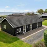 Black holiday home with terrace, garden, and sea view. Modern design with large windows.