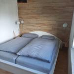 Schlafzimmer mit Doppelbett, Holzwand und Nachttischlampen.