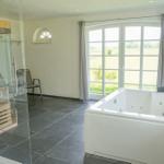 Bad mit Whirlpool, Dusche und Blick auf Felder.