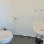 Badezimmer mit Toilette, Waschbecken und Toilettenpapierhalter.