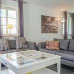 Wohnzimmer mit zwei grauen Sofas, Glas-Tisch und Wandbild.