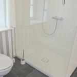 Bad mit Dusche, Toilette und Fenster. Wand mit Streifenmuster.